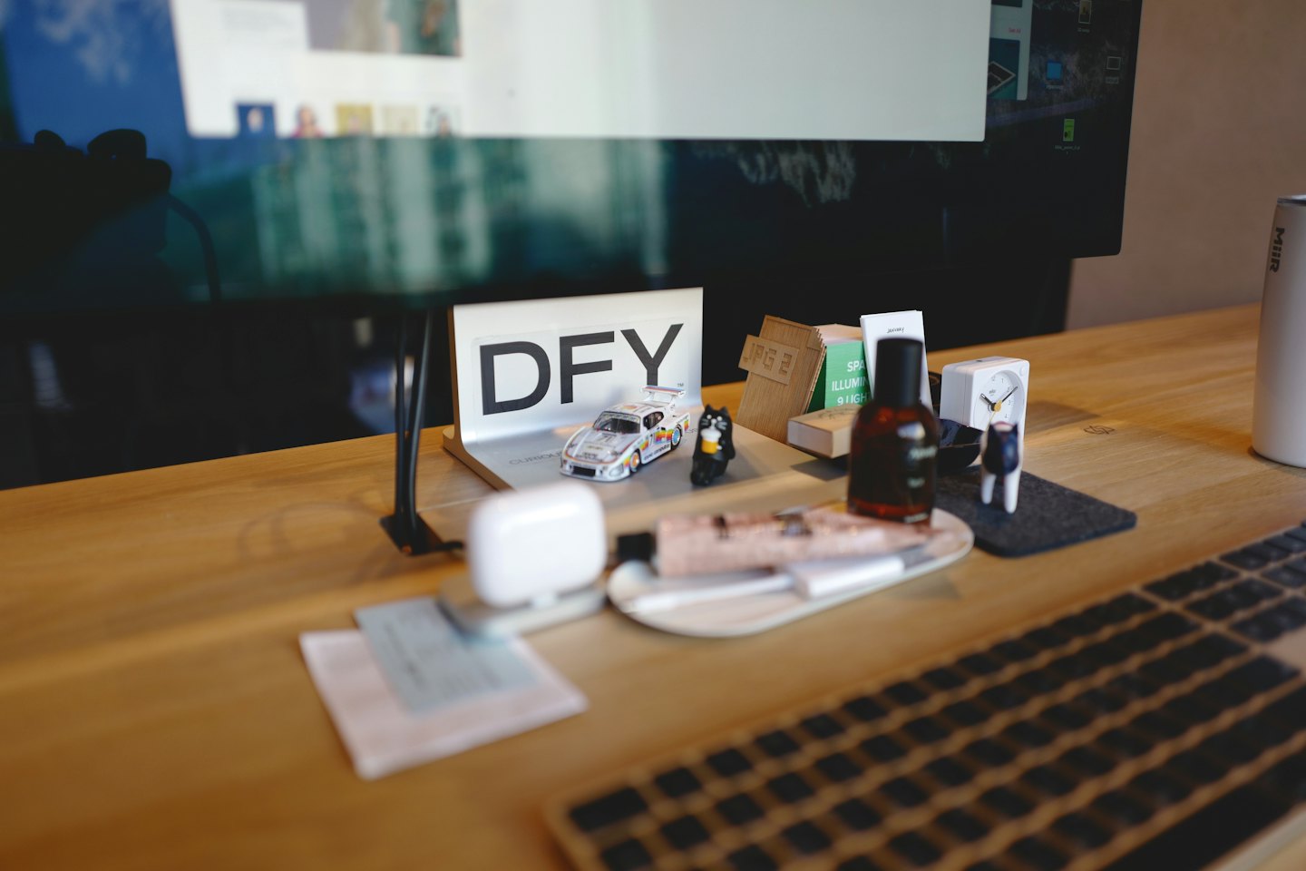 A desk with a keyboard, clock, and assorted office items.